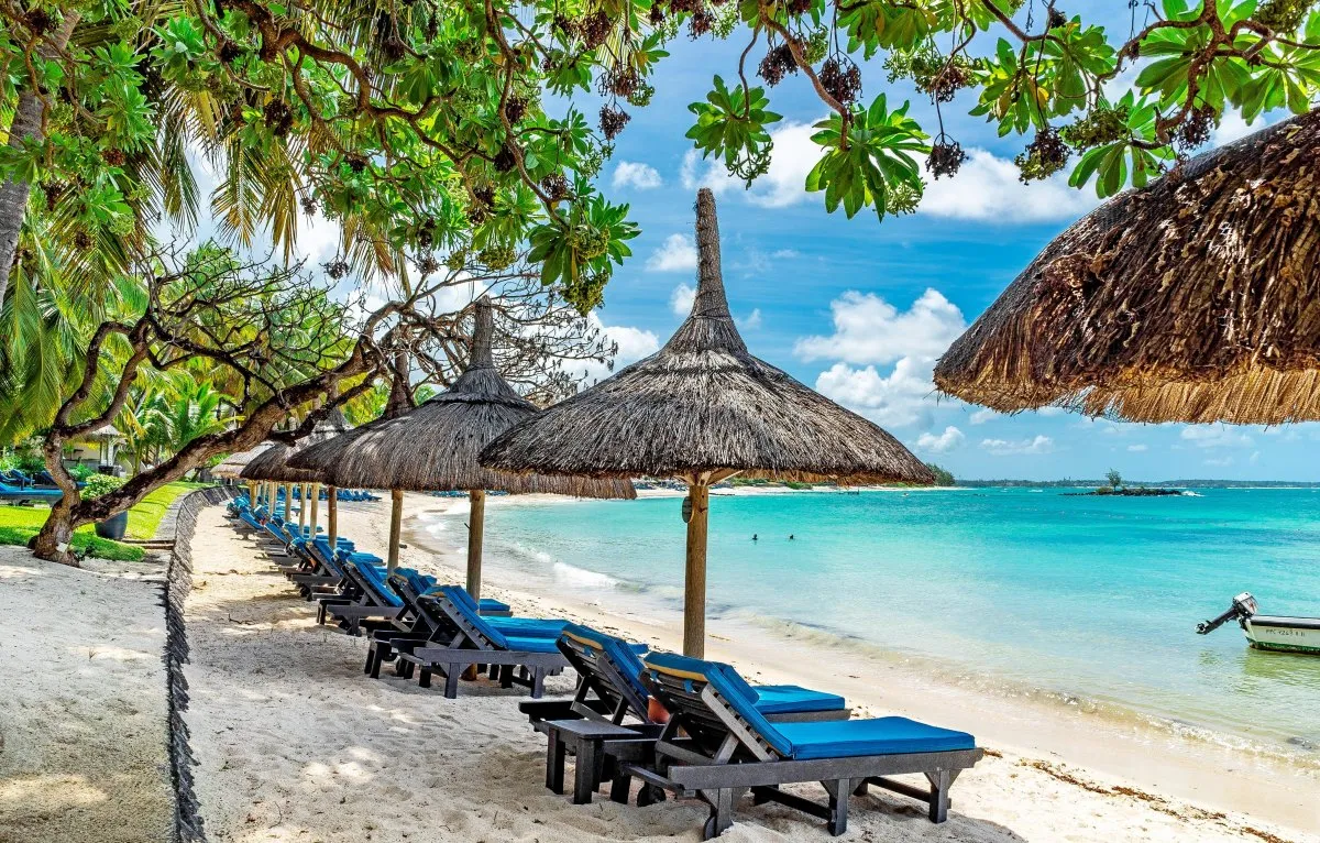 Beautiful beach at Constance Belle Mare hotel with straw umbrella and wooden deckchairs in Mauritius