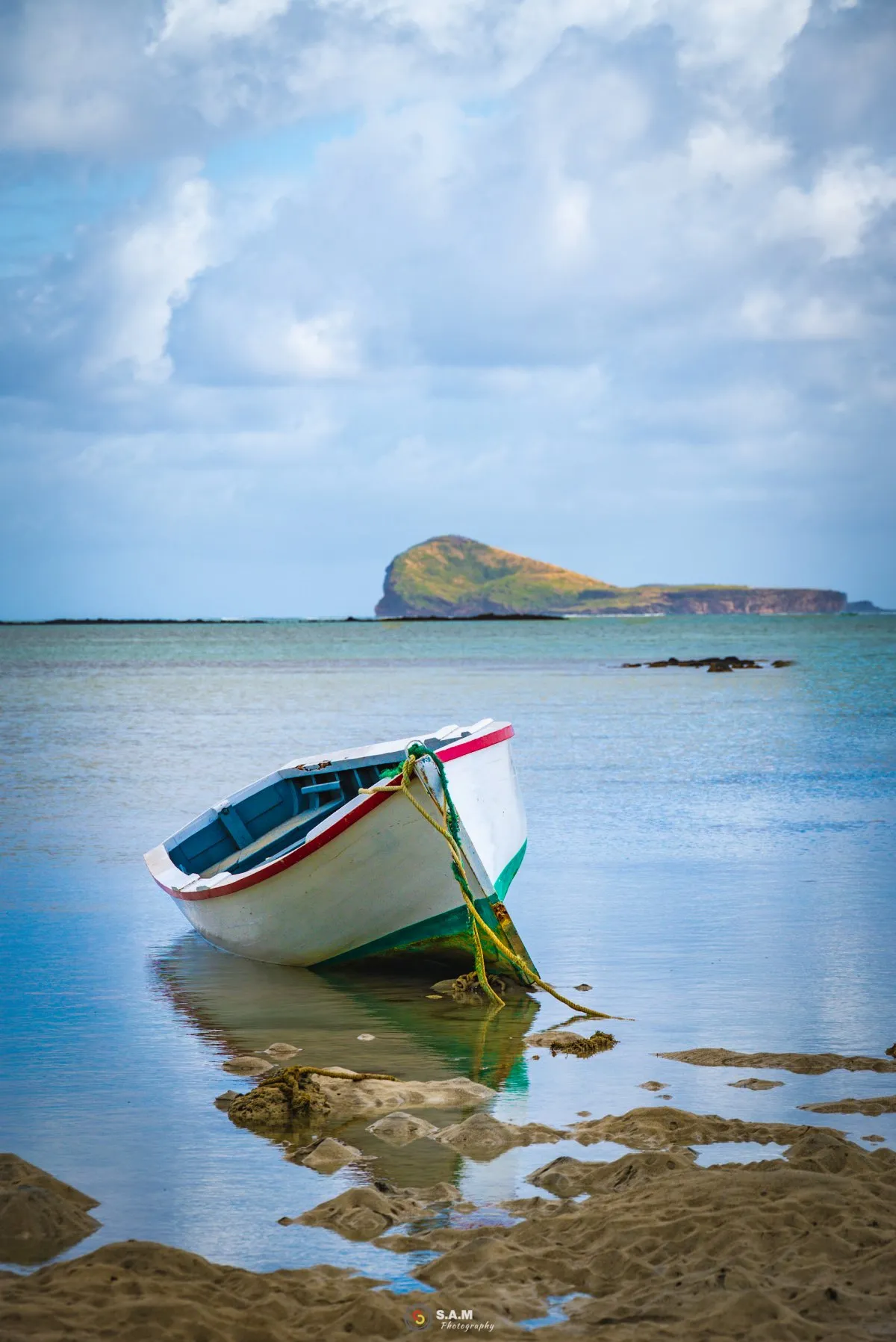 Pirogue resting on the lagoon sea floor near Coin de Mire island in Mauritius at low tide