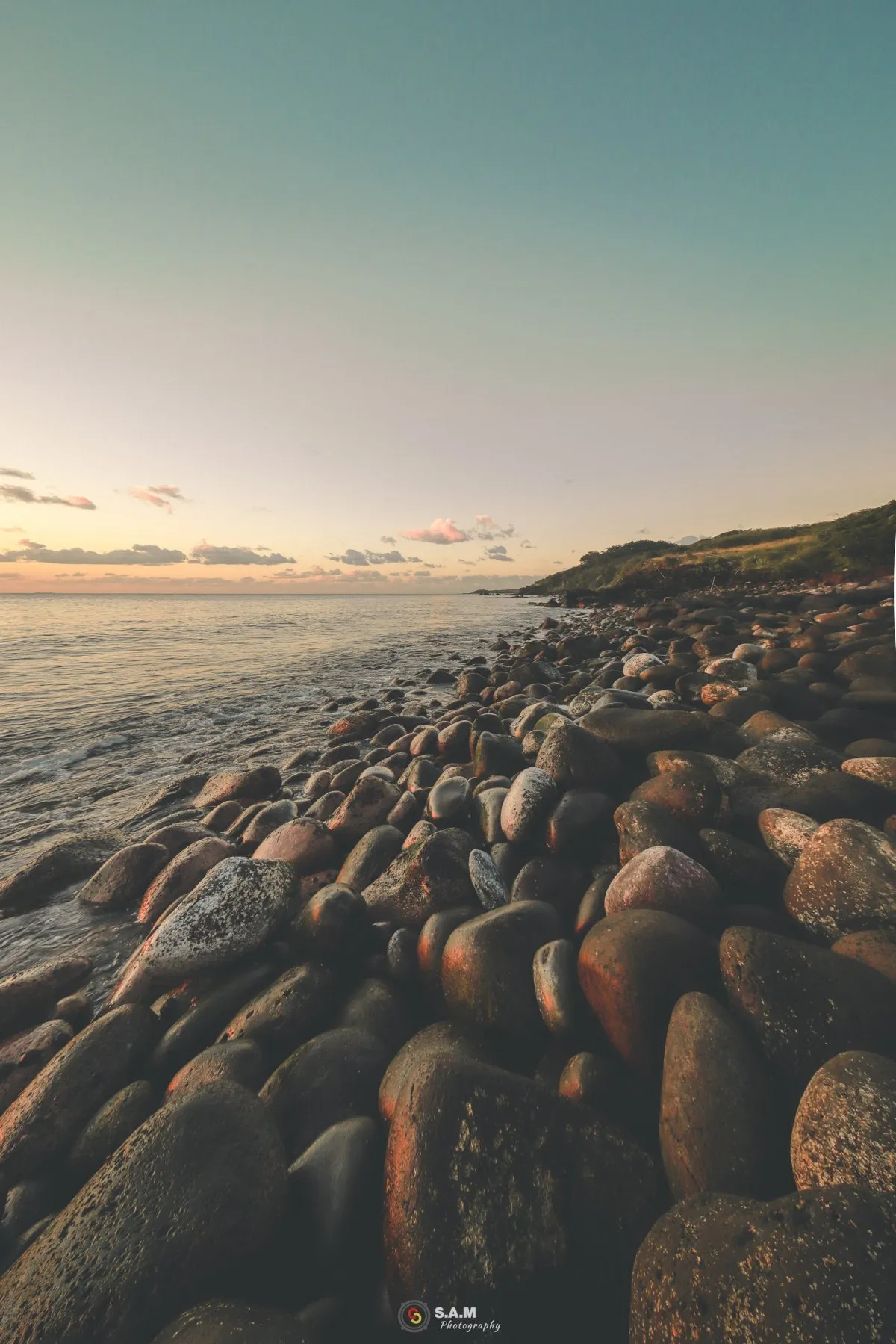 Round black and grey beach stones covering the shore at Flic en Flac, Mauritius