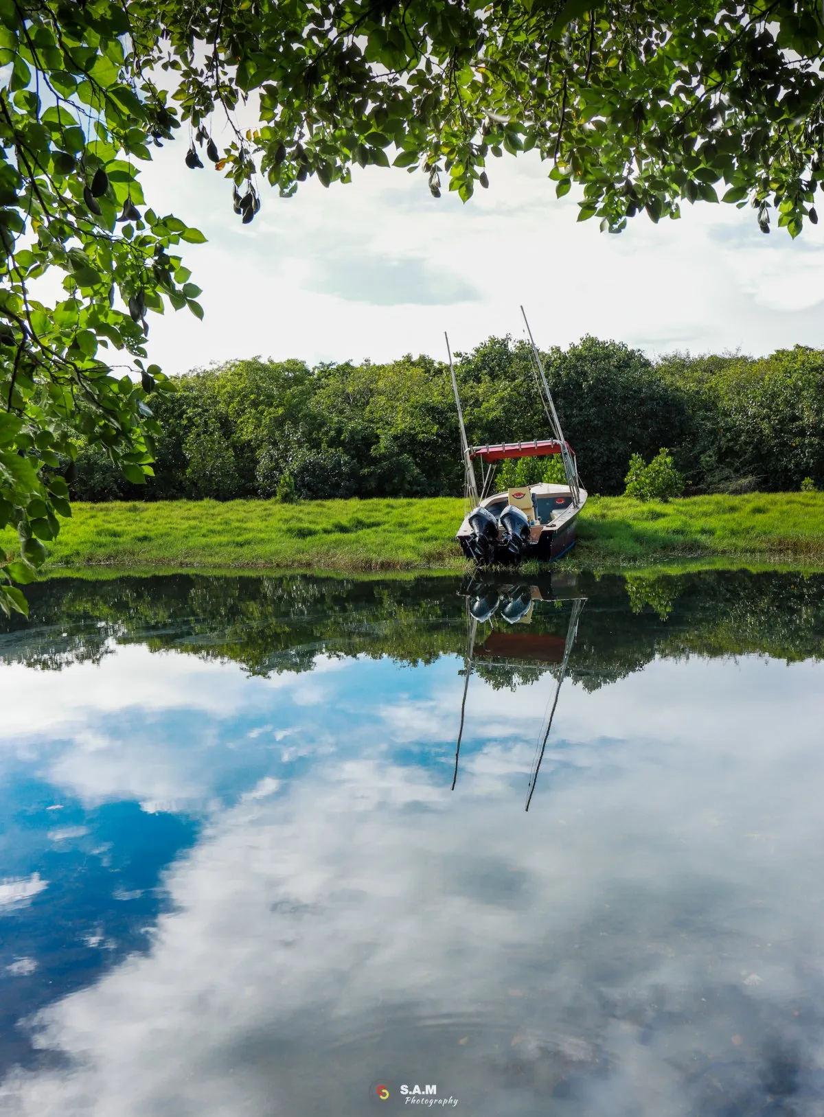 Fishing boat on grass near Tamarin Bay with calm sky reflection in Mauritius