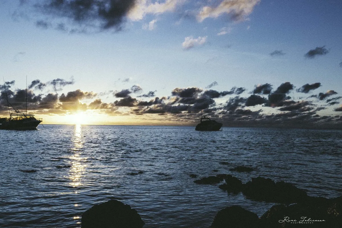 Silhouettes of fishing boats at dawn with cloudy sky over Bain Boeuf coast in Mauritius