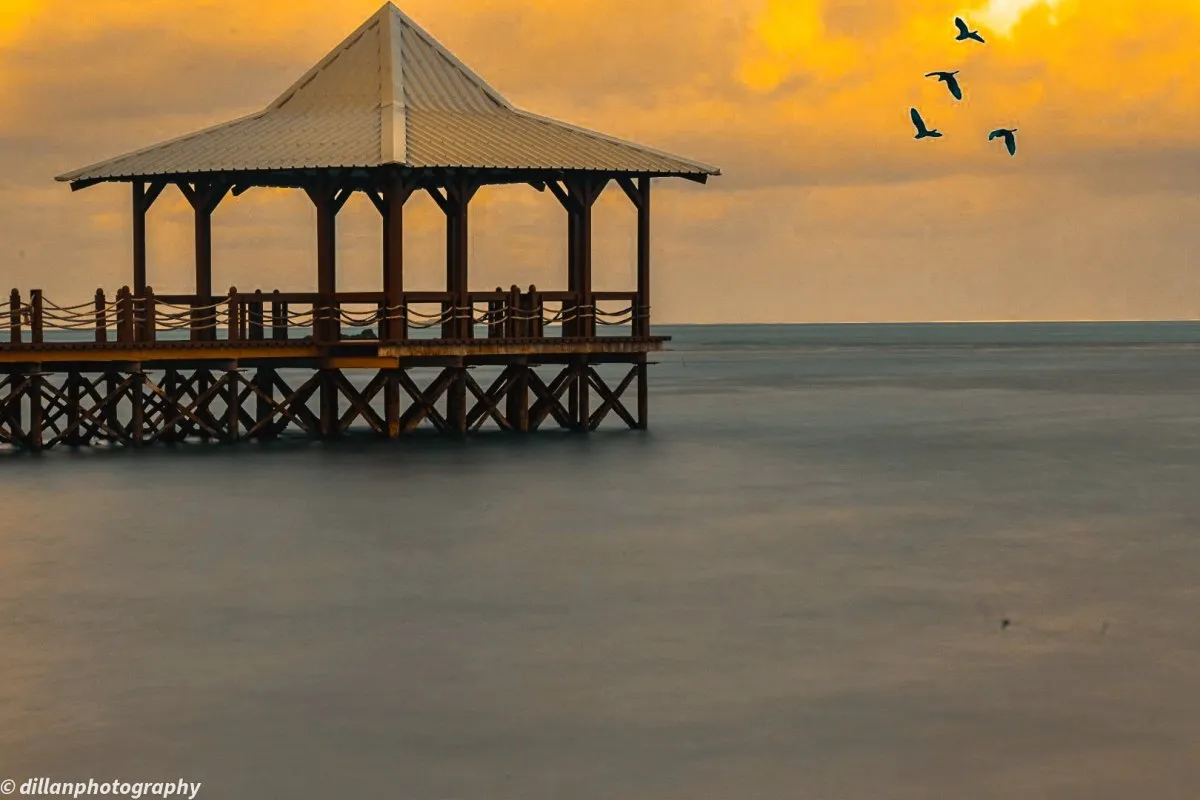 Sunrise with birds flying over jetty at Mahebourg waterfront in Mauritius
