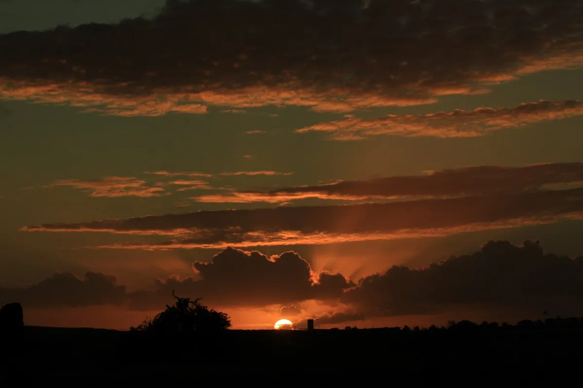 Silhouetted cottage village under a cloudy sunset sky in Mauritius