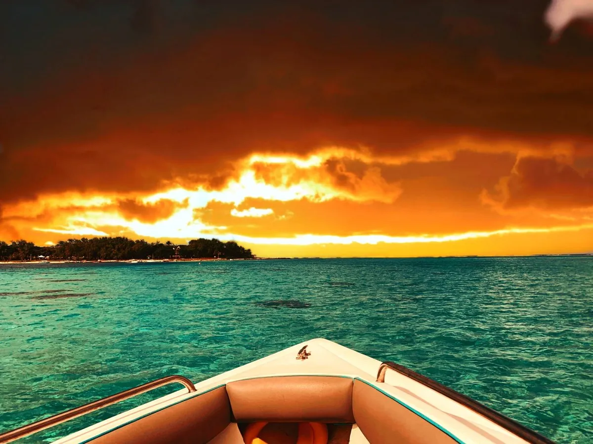 Boat sailing in dark green lagoon under early morning sunrise at Blue Bay, Mauritius