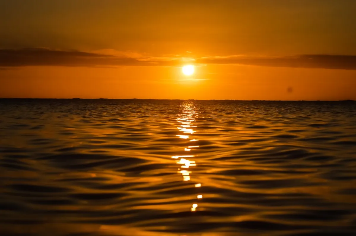 Warm sunset with round sun above calm and blurred ocean surface in Mauritius