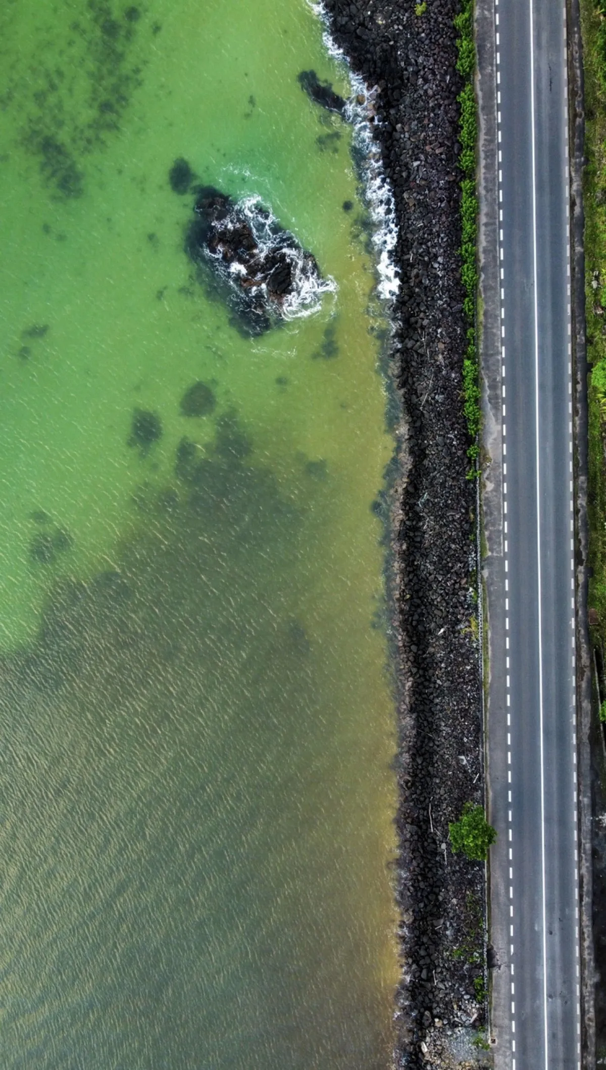 Aerial view of Maconde road alongside a rocky beach and green lagoon in Mauritius