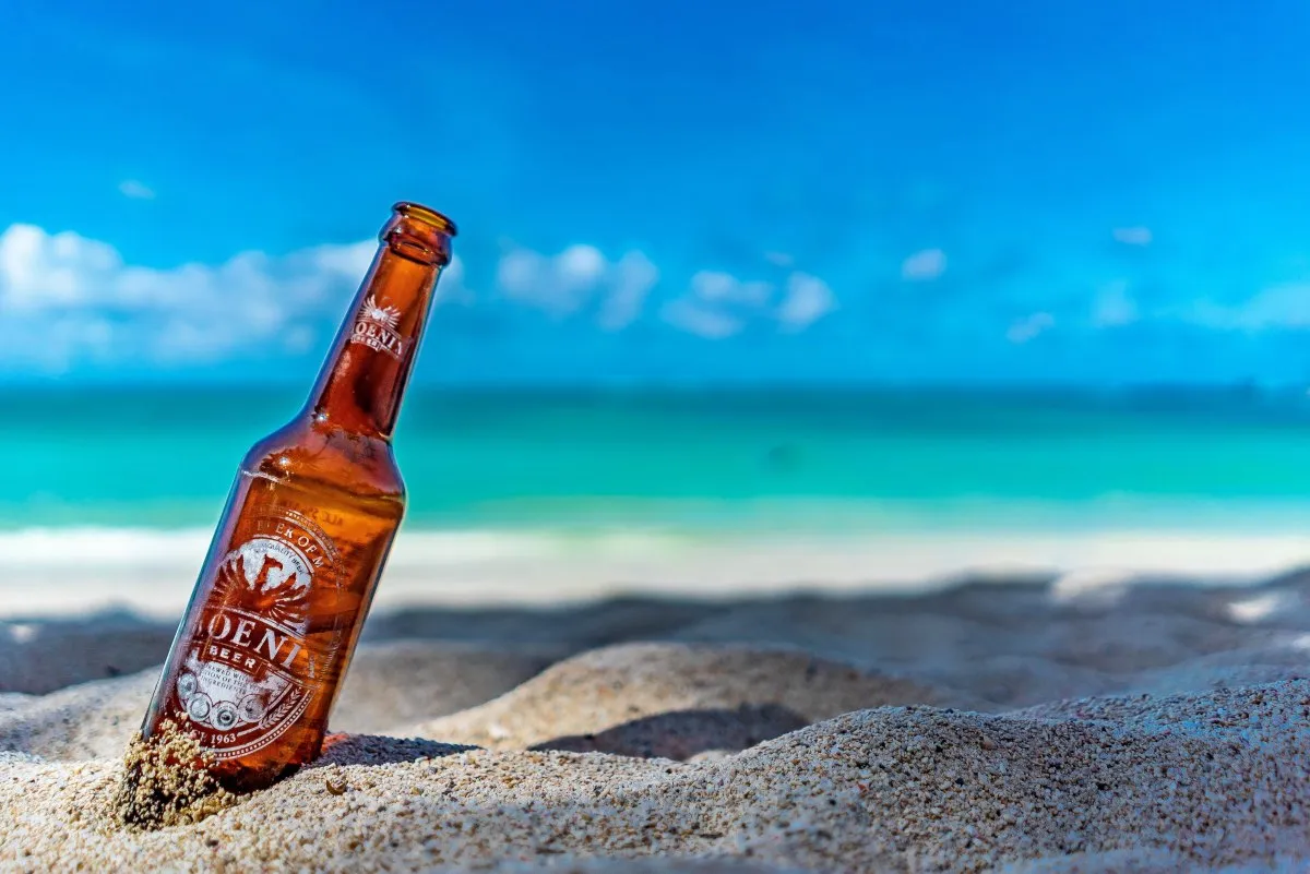 Phoenix beer bottle resting on the sand at Belle Mare beach with turquoise waters in Mauritius