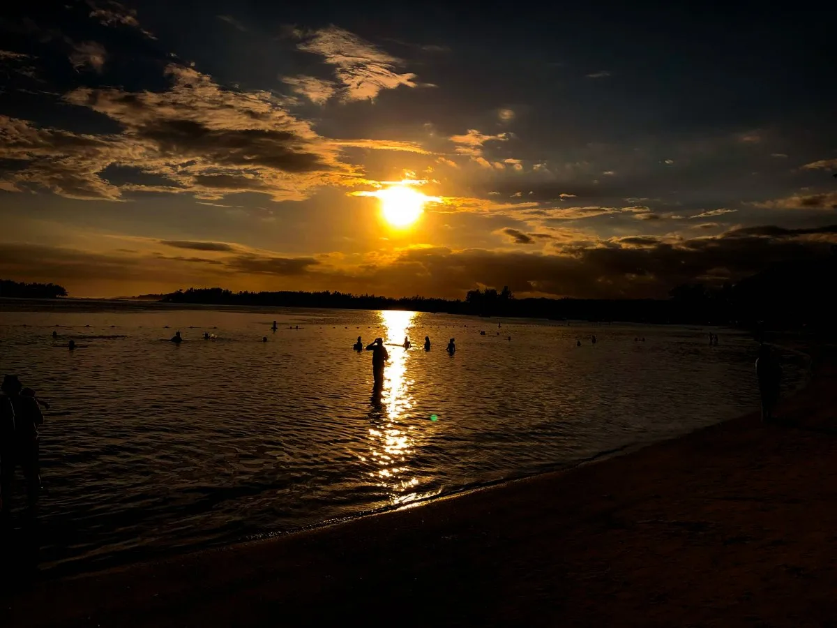 Silhouettes of people swimming in the Mauritius lagoon at sunset