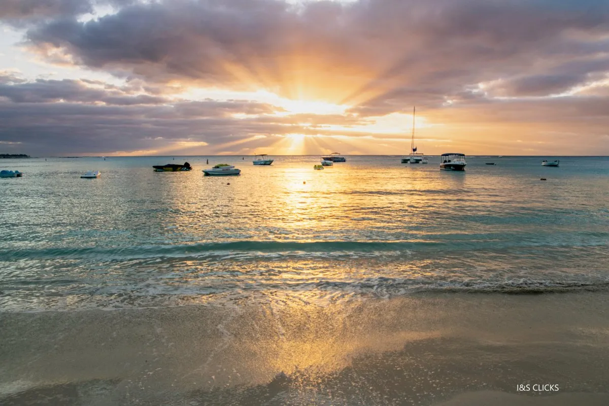 Blazing sunset over Pereybere lagoon with boats and clouds in Mauritius