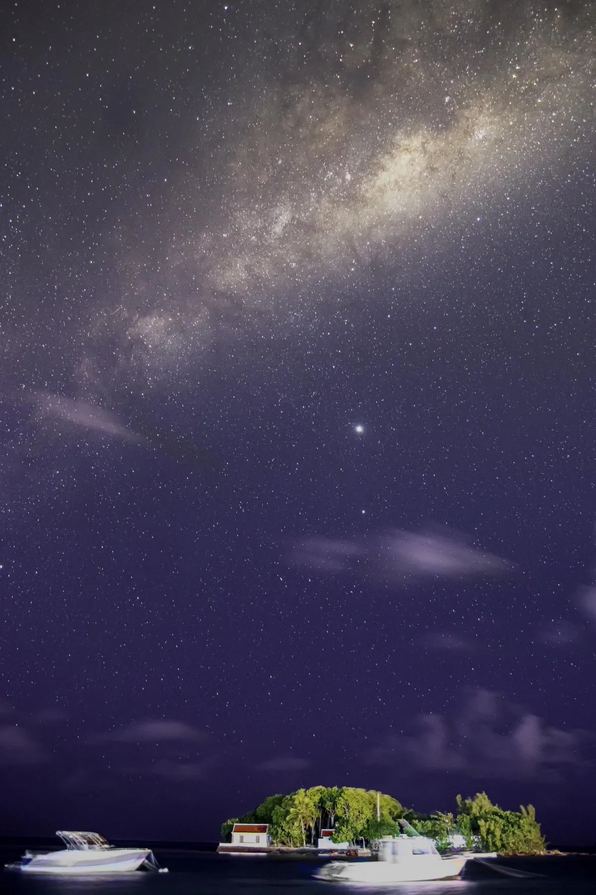 Long exposure of Milky Way and boats in Mahebourg lagoon night sky in Mauritius