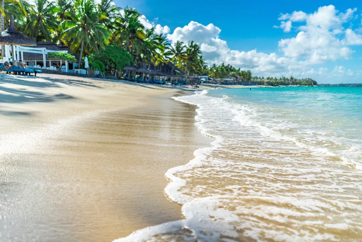 Waves reaching the coast at Belle Mare beach with turquoise water and hotel in Mauritius