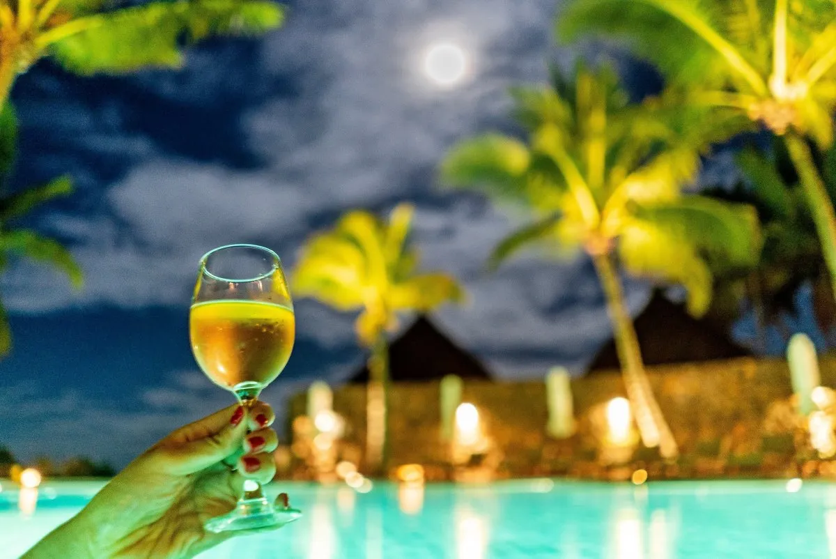 Hand holding wine glass with full moon and clouds at night in Mauritius