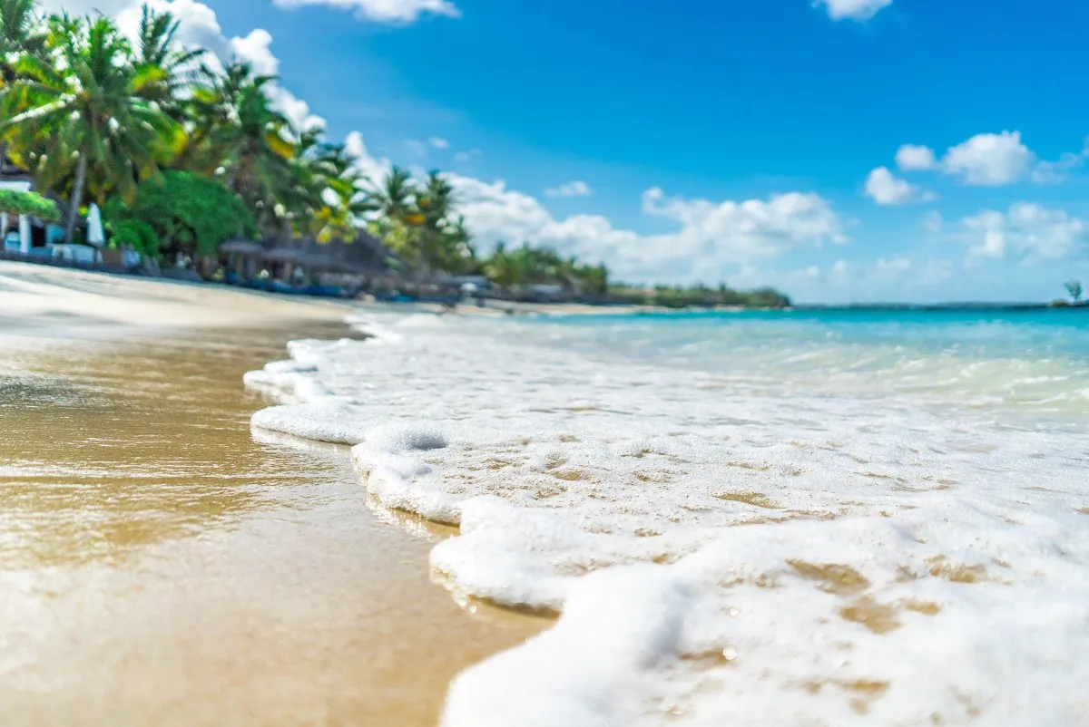 Sea foam gently reaching the sandy Belle Mare beach with calm waters in Mauritius