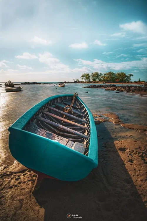 Cyan colored fishing boat on beach of Grand Gaube