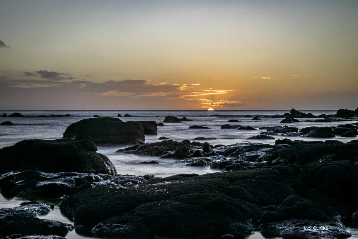 Sunset view over black rocks along the Flic en Flac coast in Mauritius