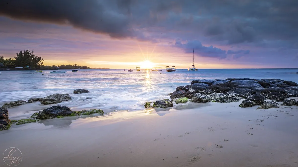Sunburst sunset with dramatic clouds over Pereybere Bay beach in Mauritius