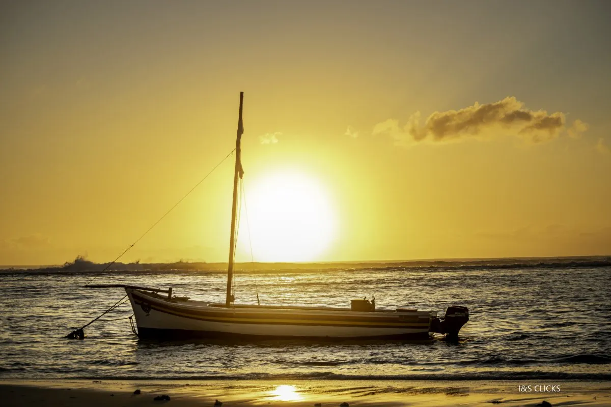 Fishing boat painted in Mauritian flag colors at sunset in Flic en Flac lagoon, Mauritius