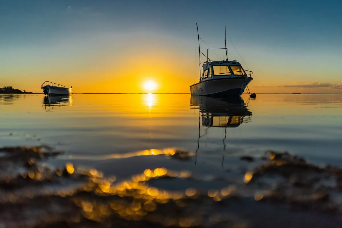Fishing boats reflecting in calm waters at sunset in Albion Bay, Mauritius