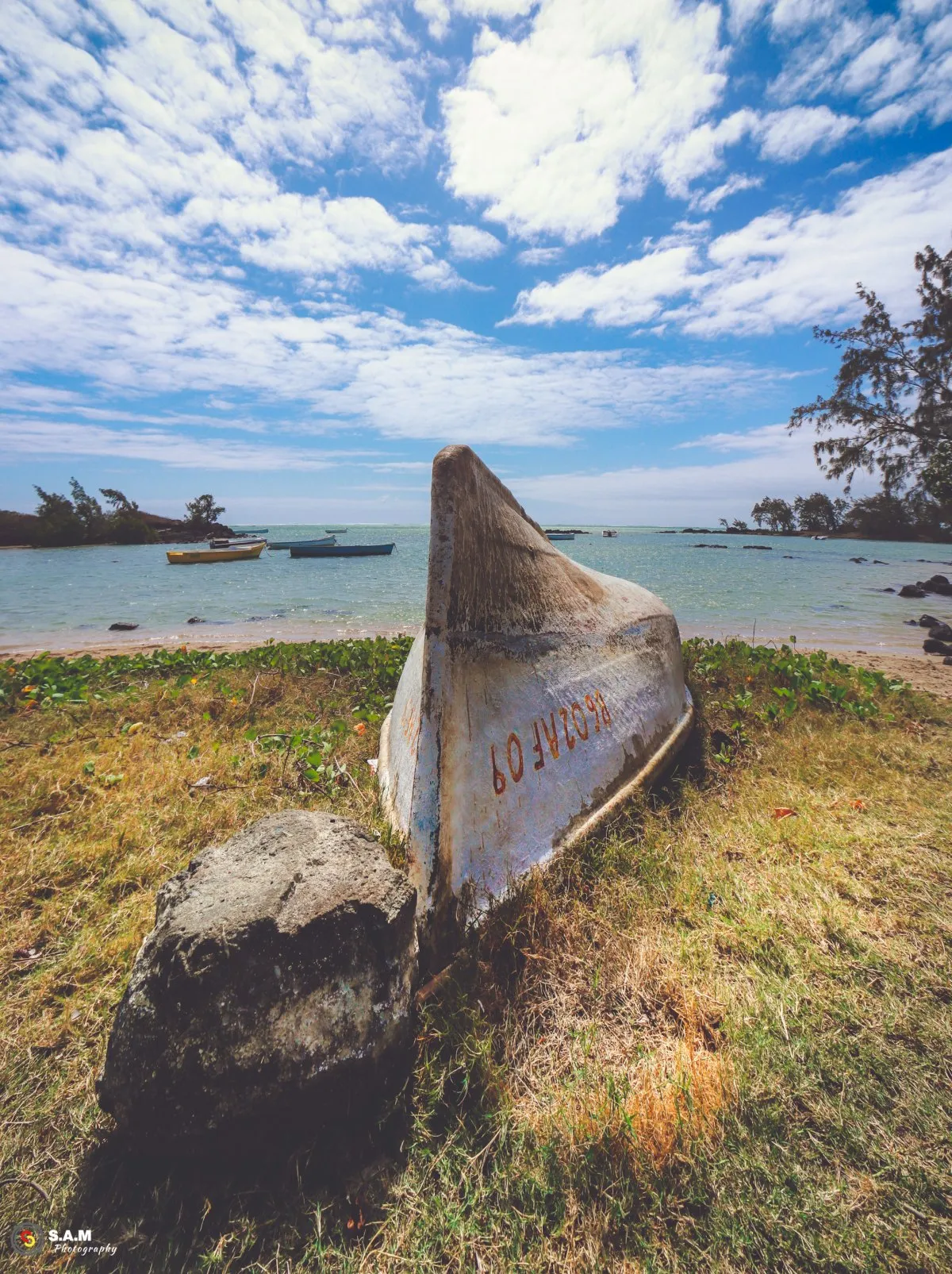 Overturned white pirogue boat on grass near lagoon on a Mauritius beach