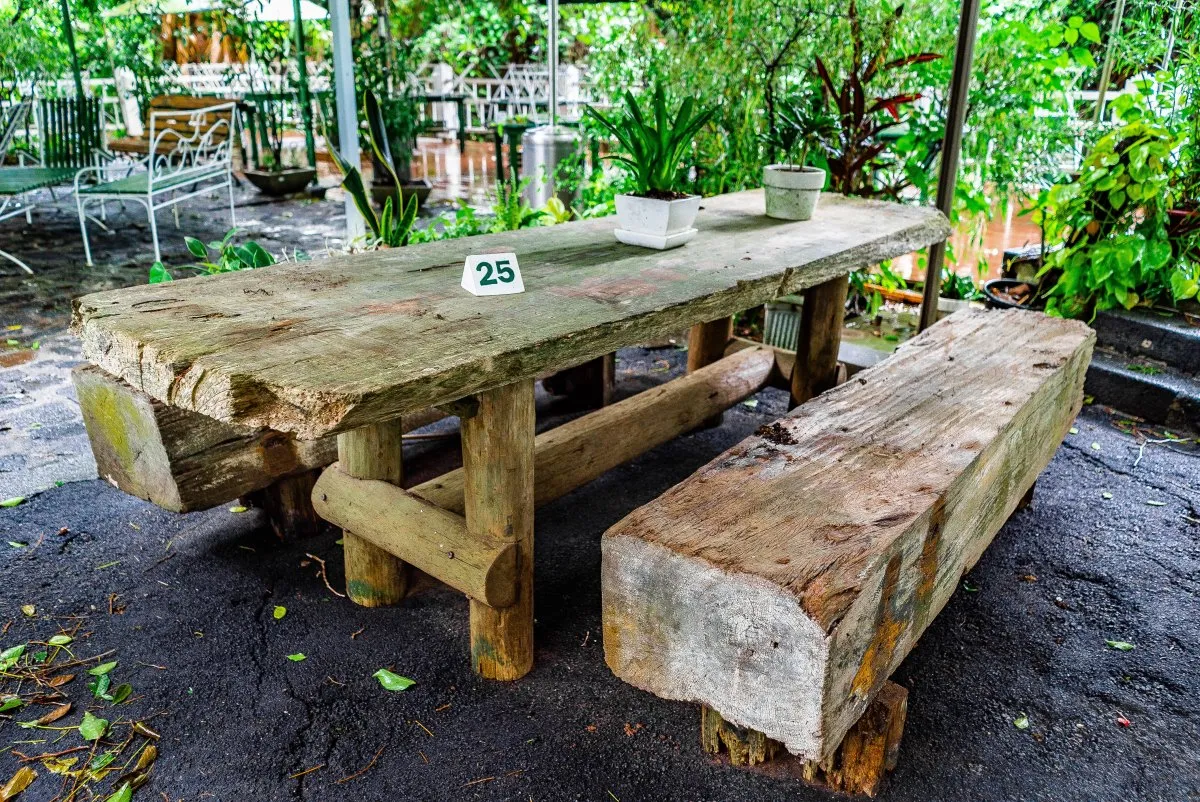 Wooden garden bench and table set surrounded by nature at Vaneron Garden Restaurant in Mauritius