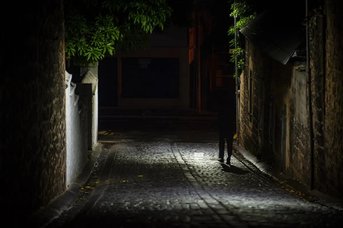 Silhouette of a man walking down a dark alley at night in Port Louis, Mauritius
