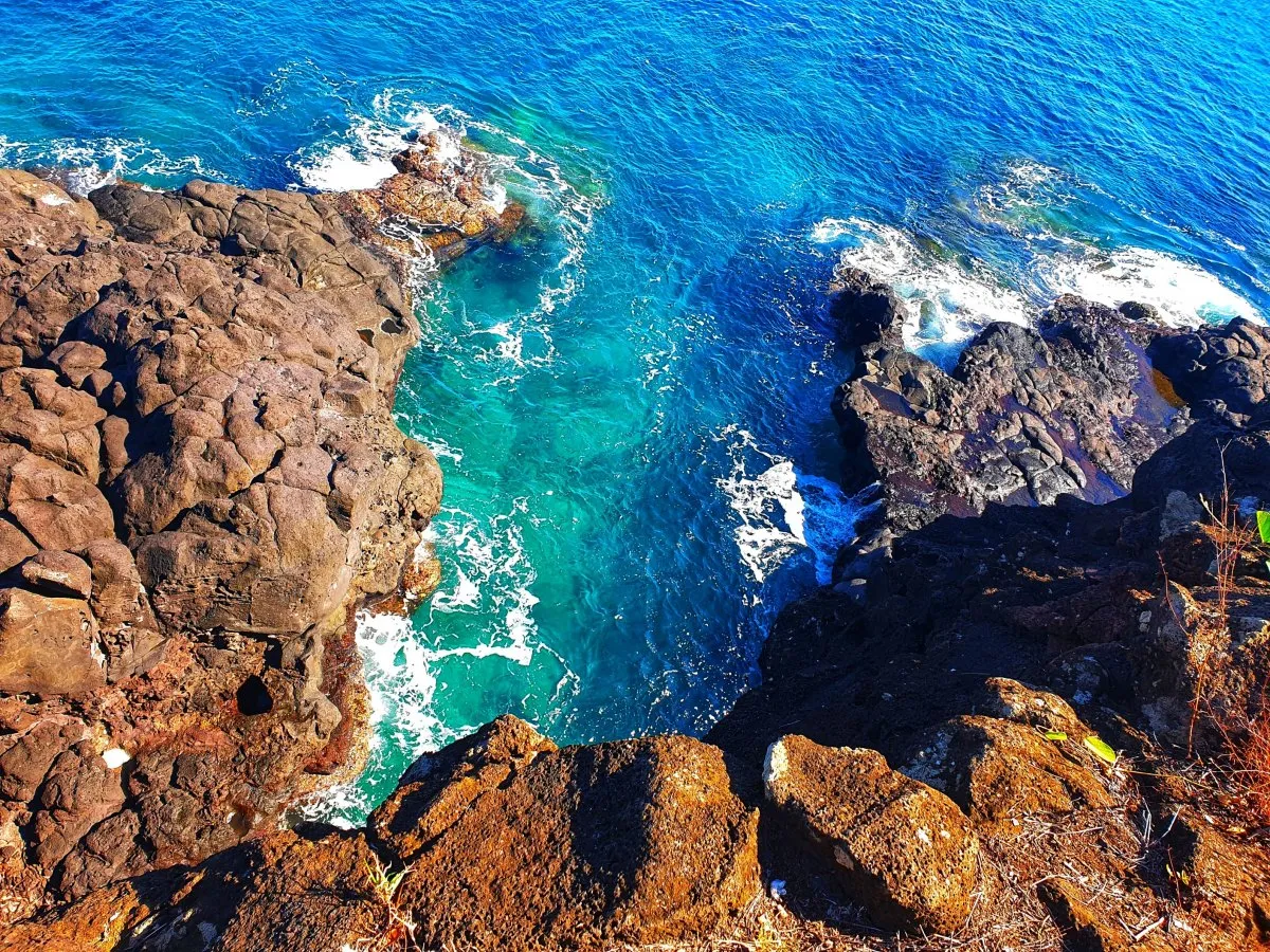 Bird's eye view of blue ocean and cliffs with large rocks below the surface in Albion, Mauritius