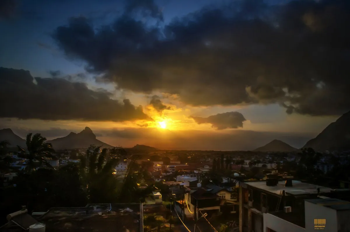 Sunset casting warm light over houses in Candos residential area, Mauritius with mountains in the background