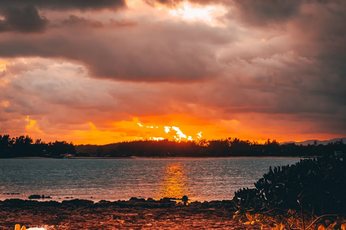 Sunset at Blue Bay beach with golden hour light and dark clouds in Mauritius