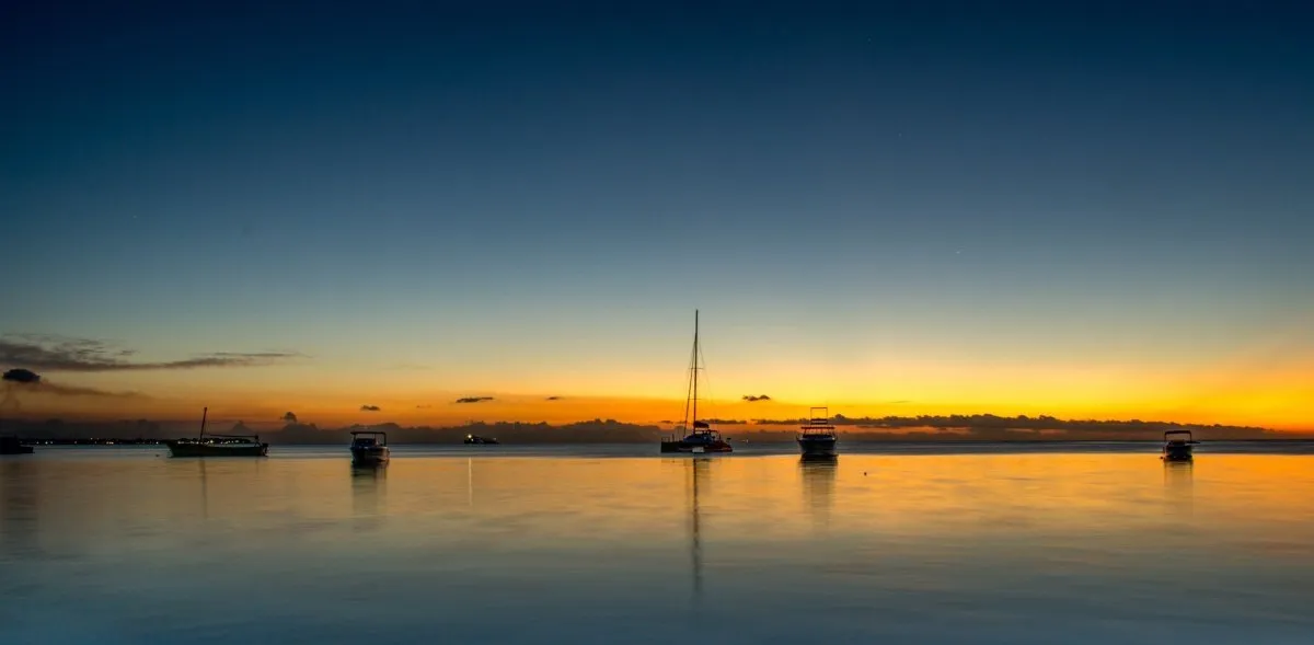 Sunset over Mont Choisy with boats on calm sea in Mauritius